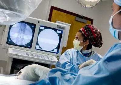 two doctors looking at a medical monitor showing electrodes being inserted near a person's spinal cord